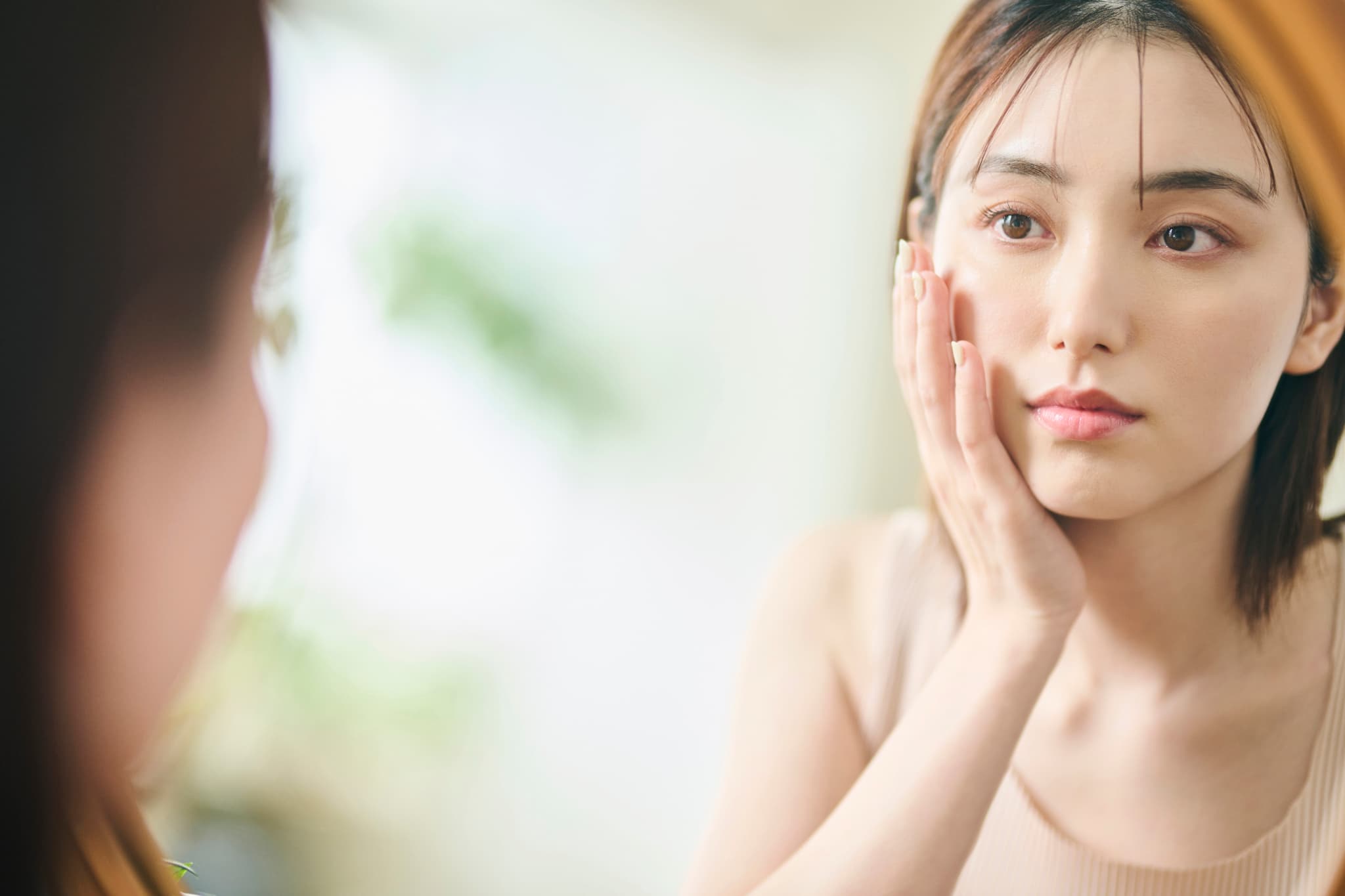 鏡で顔のズレを確認する女性