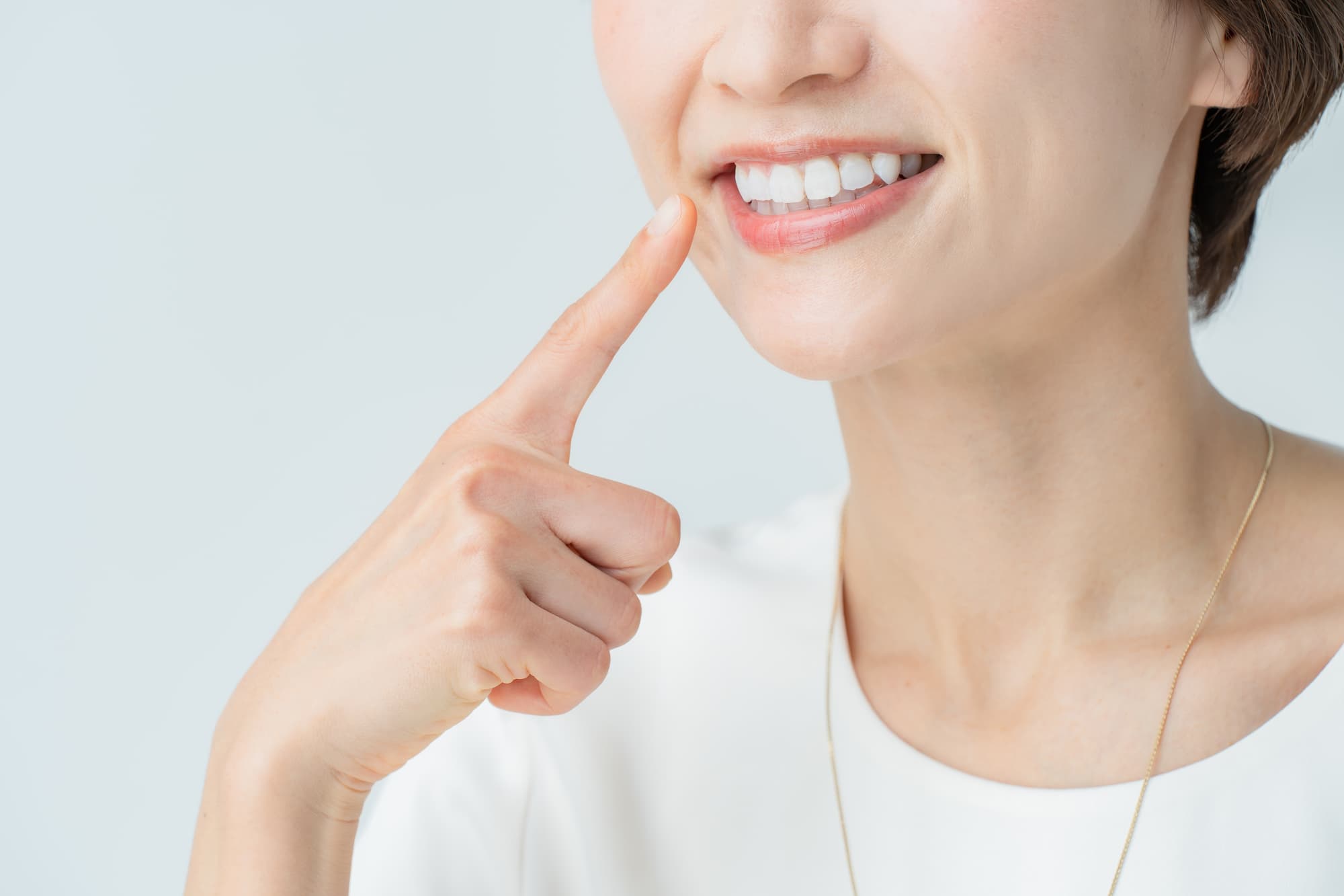 白い歯を指さす女性
